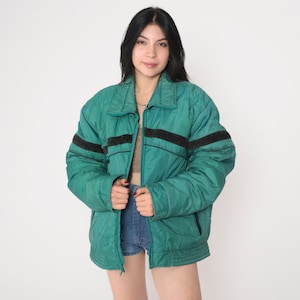 May include: A teal blue puffer jacket with black and white stripes on the sleeves. The jacket has a zipper closure and a stand-up collar.