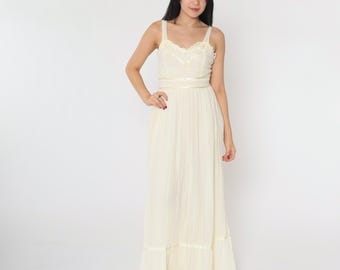 Puede incluir: Un vestido maxi blanco con un corpiño de encaje y una cinta de satén en la cintura. El vestido tiene una falda fluida con un volante escalonado en el dobladillo.