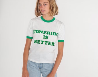 Könnte beinhalten: Weißes T-Shirt mit grünem Ringerrand und grünem Text, der "STONERIDGE IS BETTER" lautet.