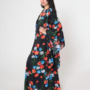 May include: A long black maxi dress with a floral print featuring red, blue, and white flowers. The dress has a V-neckline and long sleeves.