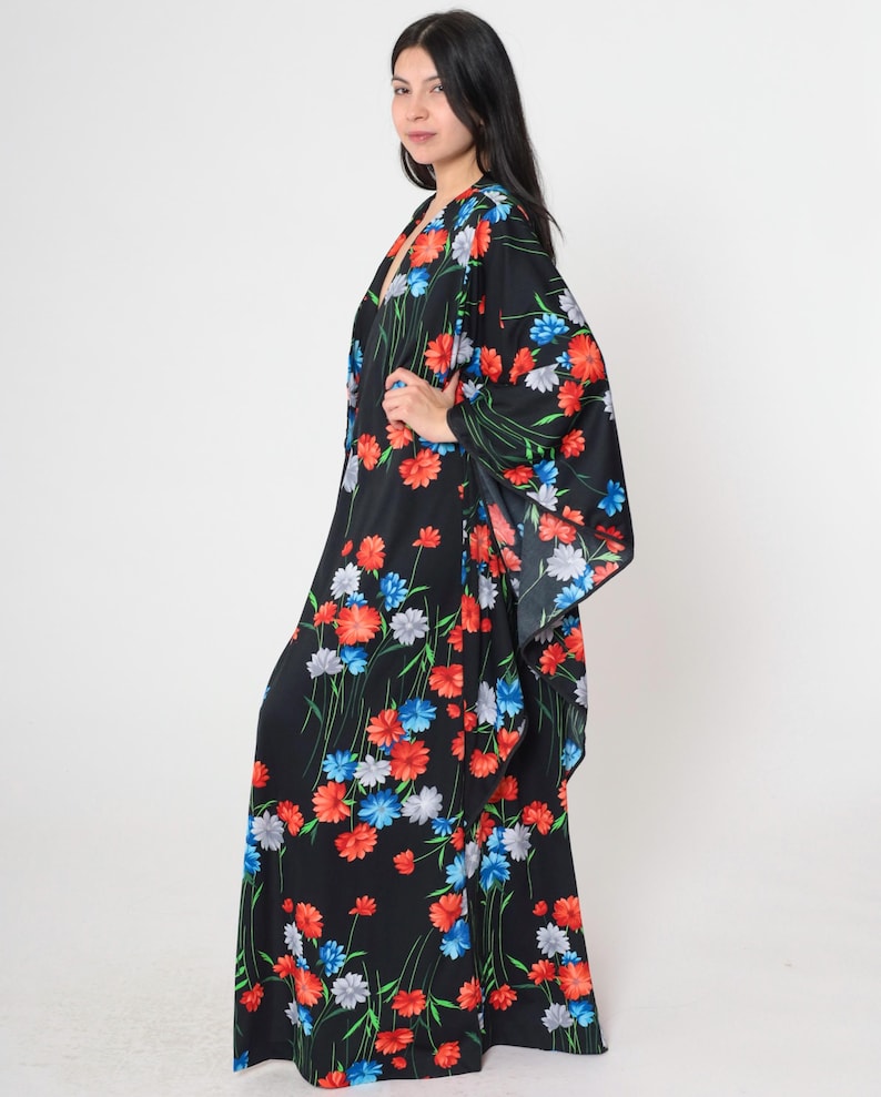 May include: A long black maxi dress with a floral print featuring red, blue, and white flowers. The dress has a V-neckline and long sleeves.