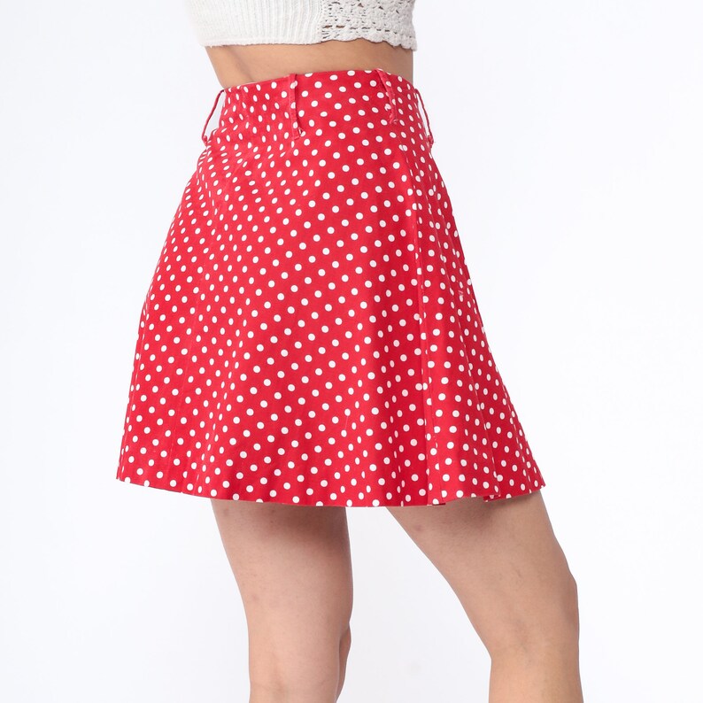 Peut inclure: Une jupe rouge &agrave; pois blancs. La jupe est trap&egrave;ze et a une taille haute.