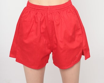 Può includere: Pantaloncini sportivi rosso brillante con elastico in vita e vestibilità rilassata. I pantaloncini sono realizzati in tessuto a tinta unita e presentano piccoli spacchi laterali sull'orlo di entrambe le gambe, dal design semplice.