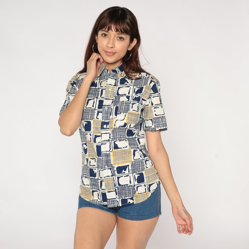 May include: A short-sleeved button-down shirt with a geometric pattern in shades of blue and yellow on a white background.