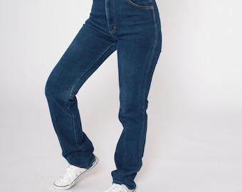 May include: A pair of dark blue denim jeans with a high waist and a straight leg fit. The jeans are worn by a person standing on a white background.