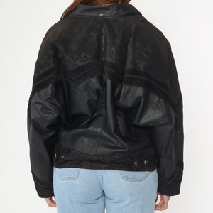 May include: Black leather jacket with a suede trim and a zipper closure. The jacket has a relaxed fit and a slightly oversized silhouette.