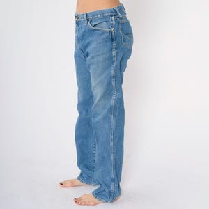 May include: A pair of light blue denim jeans with a straight leg fit. The jeans have a classic five-pocket style and a button fly.