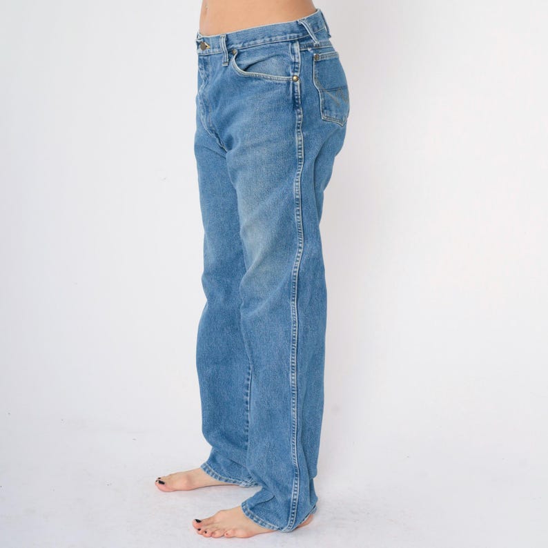 May include: A pair of light blue denim jeans with a straight leg fit. The jeans have a classic five-pocket style and a button fly.