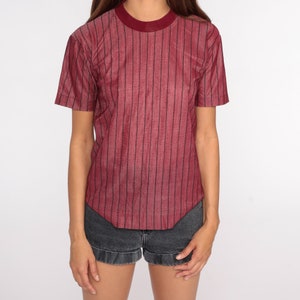 May include: A red striped short-sleeved shirt with a crew neck.