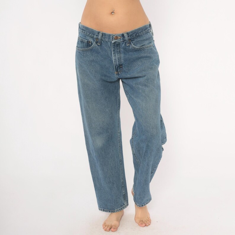 May include: Light blue denim jeans. The jeans have a classic five-pocket design, a button and zipper closure, and a straight leg fit. The denim has a faded appearance.