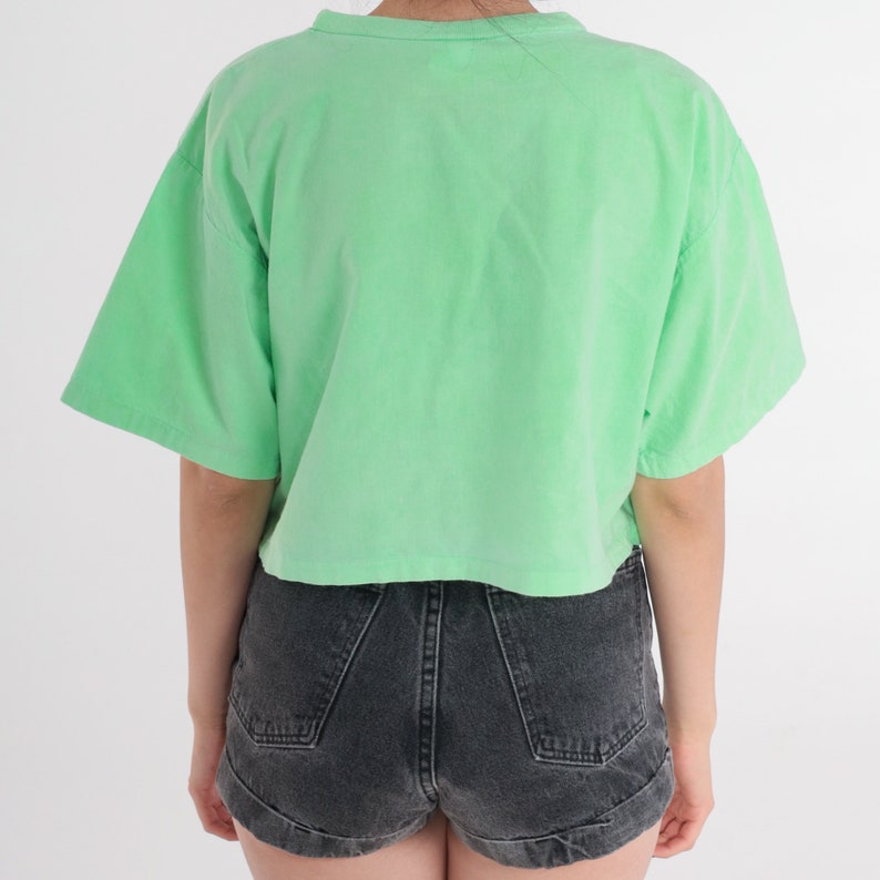 May include: A light green cropped t-shirt with short sleeves. The shirt is made of a soft, comfortable fabric and has a relaxed fit.
