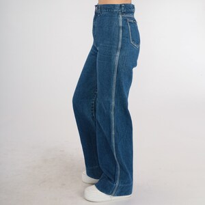 May include: A pair of blue denim jeans with a high waist and a wide leg. The jeans have a straight seam down the outside of each leg.