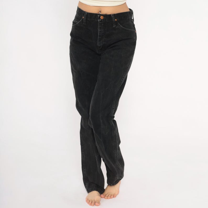May include: Black denim jeans with a classic five-pocket design. The jeans have a button and zip closure and a straight leg fit. The denim appears slightly faded, giving them a worn look. A versatile wardrobe staple.