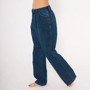 May include: Dark blue denim jeans with a classic five-pocket design. The jeans have a straight leg cut and a button and zipper closure. The denim appears to be a medium weight, suitable for everyday wear. The jeans are shown against a white background.