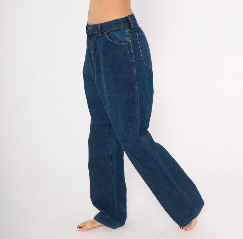 May include: Dark blue denim jeans with a classic five-pocket design. The jeans have a straight leg cut and a button and zipper closure. The denim appears to be a medium weight, suitable for everyday wear. The jeans are shown against a white background.