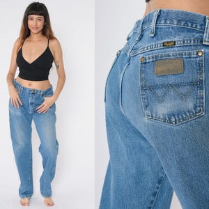 Pu&ograve; includere: Un paio di jeans in denim blu chiaro con un classico taglio a gamba dritta. I jeans hanno una vita alta e una vestibilit&agrave; rilassata lungo la gamba. I jeans presentano una toppa in pelle con la scritta "Wrangler" sul retro.