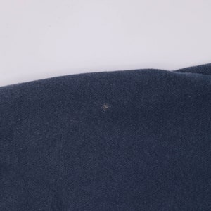 May include: A close-up of a dark blue fabric with a small white spot.