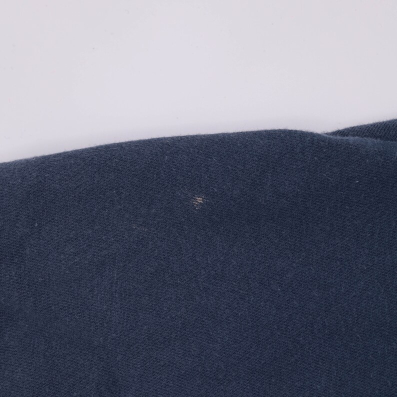 May include: A close-up of a dark blue fabric with a small white spot.