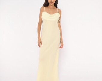 Vestido largo de tirantes finos color amarillo pálido con cuello drapeado, estilo años 70. Vestido lencero largo color crema mantequilla con detalle de volantes y lazo en la espalda. Estilo vintage, talla M.