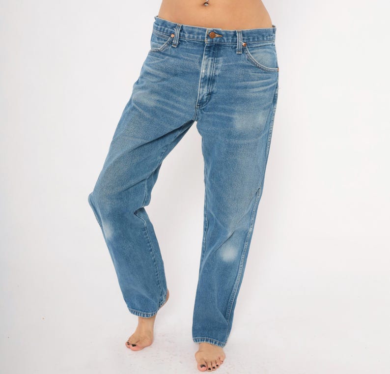 Puede incluir: Vaqueros de mezclilla azul claro con un corte recto cl&aacute;sico. Los jeans tienen cierre de bot&oacute;n y cremallera, dise&ntilde;o de cinco bolsillos y un lavado descolorido. Los jeans son usados por una persona.