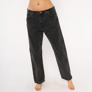 May include: Black denim jeans with a classic five-pocket design. The jeans have a straight leg fit and a faded appearance. The jeans have a button and zipper closure. The jeans are made of a durable denim material.