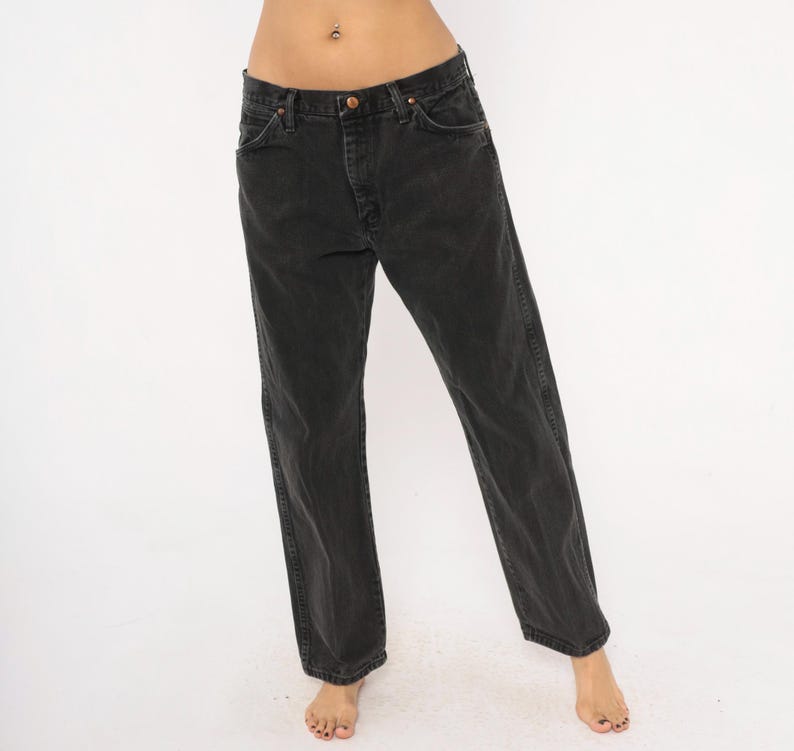 May include: Black denim jeans with a classic five-pocket design. The jeans have a straight leg fit and a faded appearance. The jeans have a button and zipper closure. The jeans are made of a durable denim material.