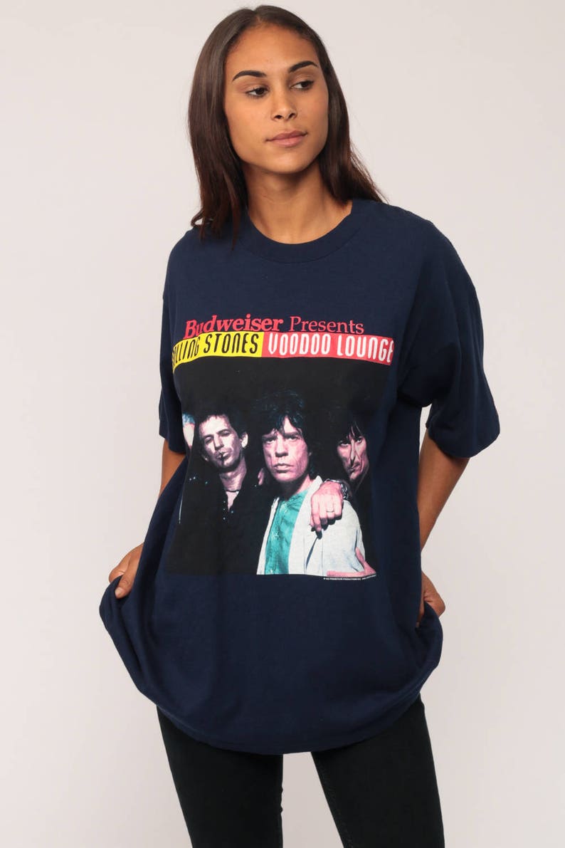 May include: Navy blue t-shirt featuring a graphic of The Rolling Stones with the text "Budweiser Presents Rolling Stones Voodoo Lounge". The shirt has a crew neck and short sleeves.