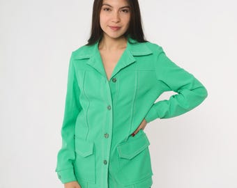 May include: A vibrant green jacket featuring a collared design, two front pockets, and contrasting stitching. The jacket has long sleeves and is fastened with buttons. The jacket is worn with blue jeans.