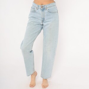 May include: Light blue denim jeans with a classic five-pocket design. The jeans have a straight leg fit and a button and zipper closure. The light wash denim has subtle fading and wear, giving them a vintage look. A timeless wardrobe staple.