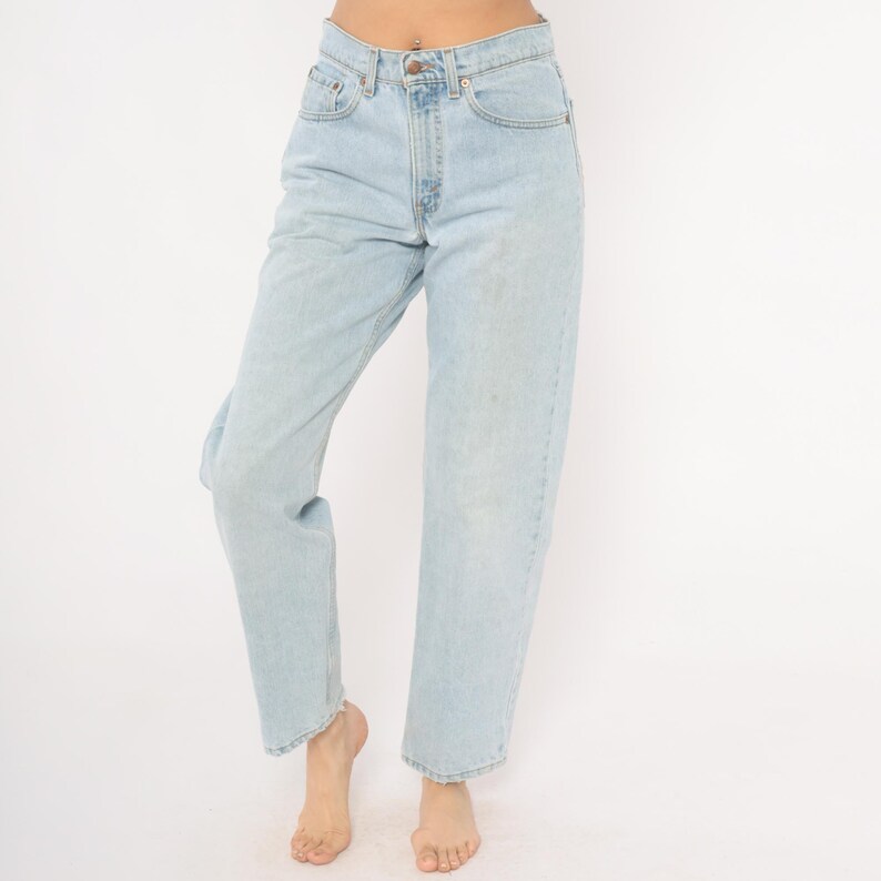 May include: Light blue denim jeans with a classic five-pocket design. The jeans have a straight leg fit and a button and zipper closure. The light wash denim has subtle fading and wear, giving them a vintage look. A timeless wardrobe staple.