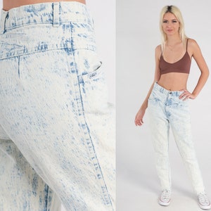 May include: High-waisted acid wash jeans in a light blue colour with a faded look. The jeans have a relaxed fit and a straight leg.