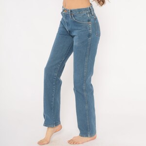 May include: Light blue denim jeans with a classic straight-leg fit. The jeans feature a traditional five-pocket design, a button and zipper closure, and are made of durable denim material. The jeans are a versatile wardrobe staple.