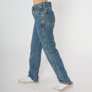 Puede incluir: Vaqueros de mezclilla azul claro con un corte recto cl&aacute;sico. Los jeans presentan un dise&ntilde;o tradicional de cinco bolsillos, cierre de bot&oacute;n y cremallera, y un lavado descolorido. El modelo lleva zapatillas blancas. Un b&aacute;sico atemporal del armario.