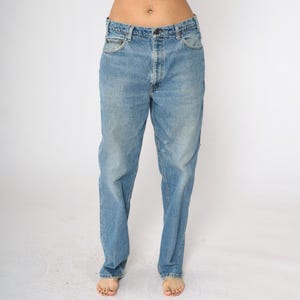 May include: A pair of light blue denim jeans with a straight leg fit. The jeans have a faded wash and a slightly distressed look.