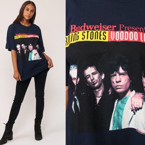 May include: Navy blue t-shirt featuring a graphic of The Rolling Stones with the text "Budweiser Presents Rolling Stones Voodoo Lounge." The image shows the band members in a close-up shot. The shirt is a classic band merchandise.