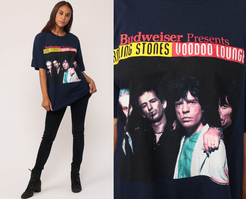May include: Navy blue t-shirt featuring a graphic of The Rolling Stones with the text "Budweiser Presents Rolling Stones Voodoo Lounge." The image shows the band members in a close-up shot. The shirt is a classic band merchandise.