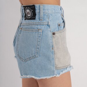Puede incluir: Pantalones cortos de mezclilla azul claro con dobladillo deshilachado y un bolsillo de parche gris contrastante en la parte posterior. Los pantalones cortos tienen una etiqueta negra con el texto "Long Wear Quality Product" y un logotipo.