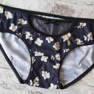 Pu&ograve; includere: Intimo in pizzo nero con stampa floreale e un pannello in rete trasparente sul davanti.
