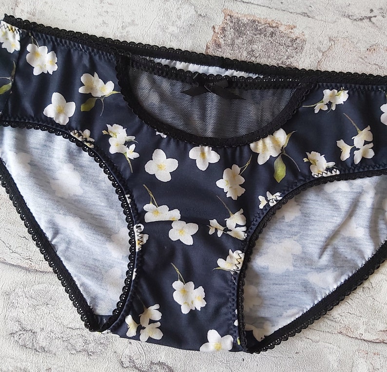 Pu&ograve; includere: Intimo in pizzo nero con stampa floreale e un pannello in rete trasparente sul davanti.
