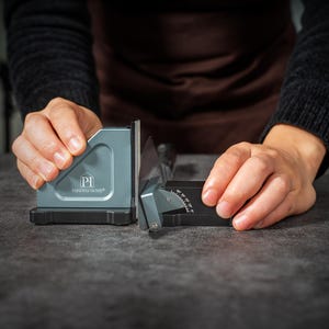 May include: A blue and black knife sharpening tool featuring the Parkway Home logo on the side. The device includes an adjustable angle guide with markings from 0 to 40 degrees, designed to hold a knife blade securely in place for sharpening.