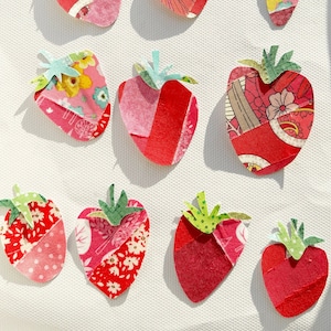 Può includere: Una collezione di 12 fragole di stoffa fatte a mano in varie tonalità di rosso, rosa e verde. Ogni fragola è realizzata con tessuti a motivi diversi e ha un design unico.
