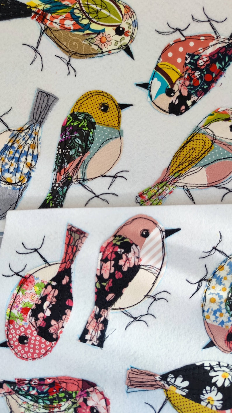 May include: A collection of fabric bird appliqu&eacute;s in various colors and patterns. The birds feature floral, polka dot, and striped designs, with black stitched outlines and delicate wire legs. The background is a soft white.