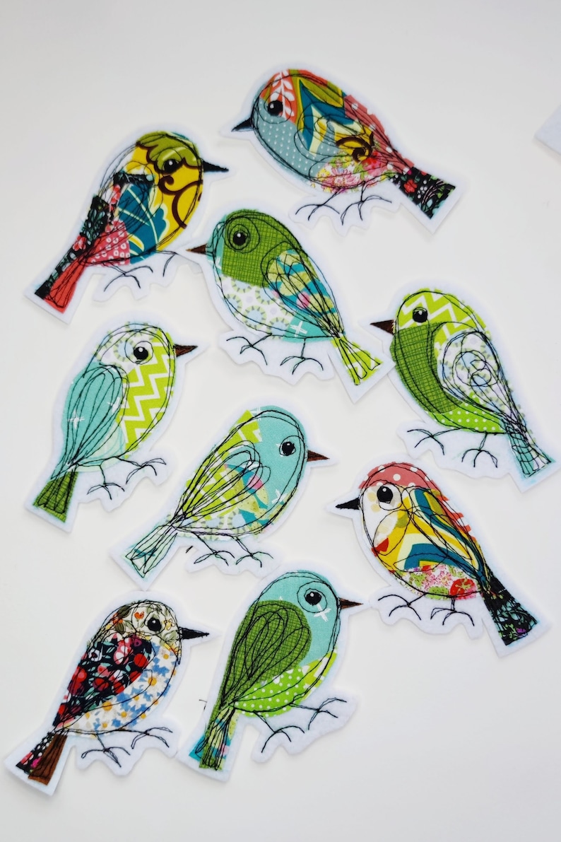 May include: A collection of nine colorful bird patches with intricate fabric patterns and embroidered details. Each bird features a unique design with various colors, including green, blue, yellow, and red, and is outlined with black stitching.