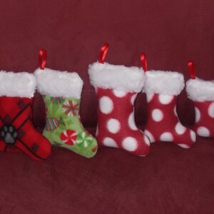 May include: Five red and white Christmas stockings with white fur trim. The stockings have different patterns, including polka dots, plaid, and candy canes.