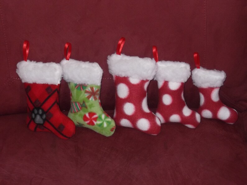 May include: Five red and white Christmas stockings with white fur trim. The stockings have different patterns, including polka dots, plaid, and candy canes.