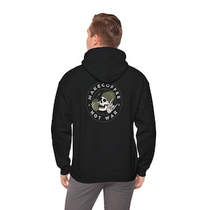May include: Black hooded sweatshirt with a white circle graphic on the back. The graphic features a skull wearing a green beanie and holding a coffee cup. The text around the graphic reads "Make Coffee Not War."