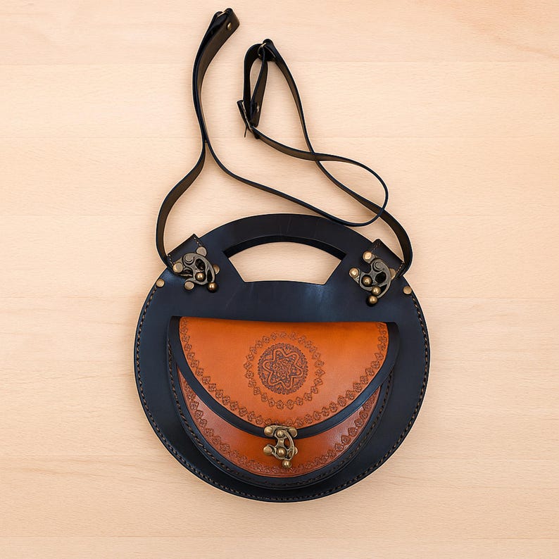 Handmade round crossbody bag crafted from black and brown genuine leather, featuring a Turkish floral motif burned and painted by hand. Elegant, structured, and artisan-made—this boho shoulder purse combines traditional design with practical use. A unique accessory from Türkiye.