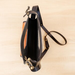 Handmade round crossbody bag crafted from black and brown genuine leather, featuring a Turkish floral motif burned and painted by hand. Elegant, structured, and artisan-made—this boho shoulder purse combines traditional design with practical use. A unique accessory from Türkiye.
