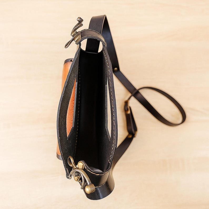 Handmade round crossbody bag crafted from black and brown genuine leather, featuring a Turkish floral motif burned and painted by hand. Elegant, structured, and artisan-made—this boho shoulder purse combines traditional design with practical use. A unique accessory from Türkiye.