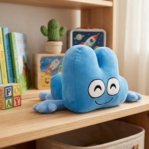 May include: A large, plush, light blue number four character with a smiling face and white eyes. The plush toy is lying on a wooden shelf, with other decorative items in the background, including books and a cactus.